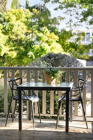 Un patio al aire libre con una mesa y sillas, rodeado por una barandilla y follaje.