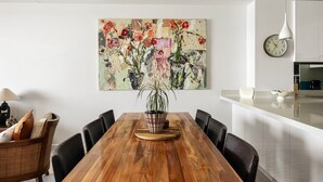Un coin repas avec une table en bois, des chaises, un vase de fleurs et un tableau accroché au mur.