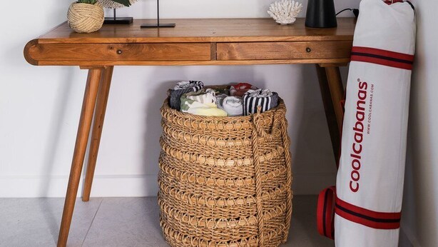 Un bureau en bois avec une lampe, des miroirs décoratifs et un panier en osier.