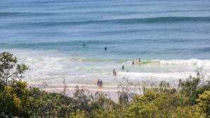 Une plage où l’on voit des gens se baigner et se promener le long du rivage.