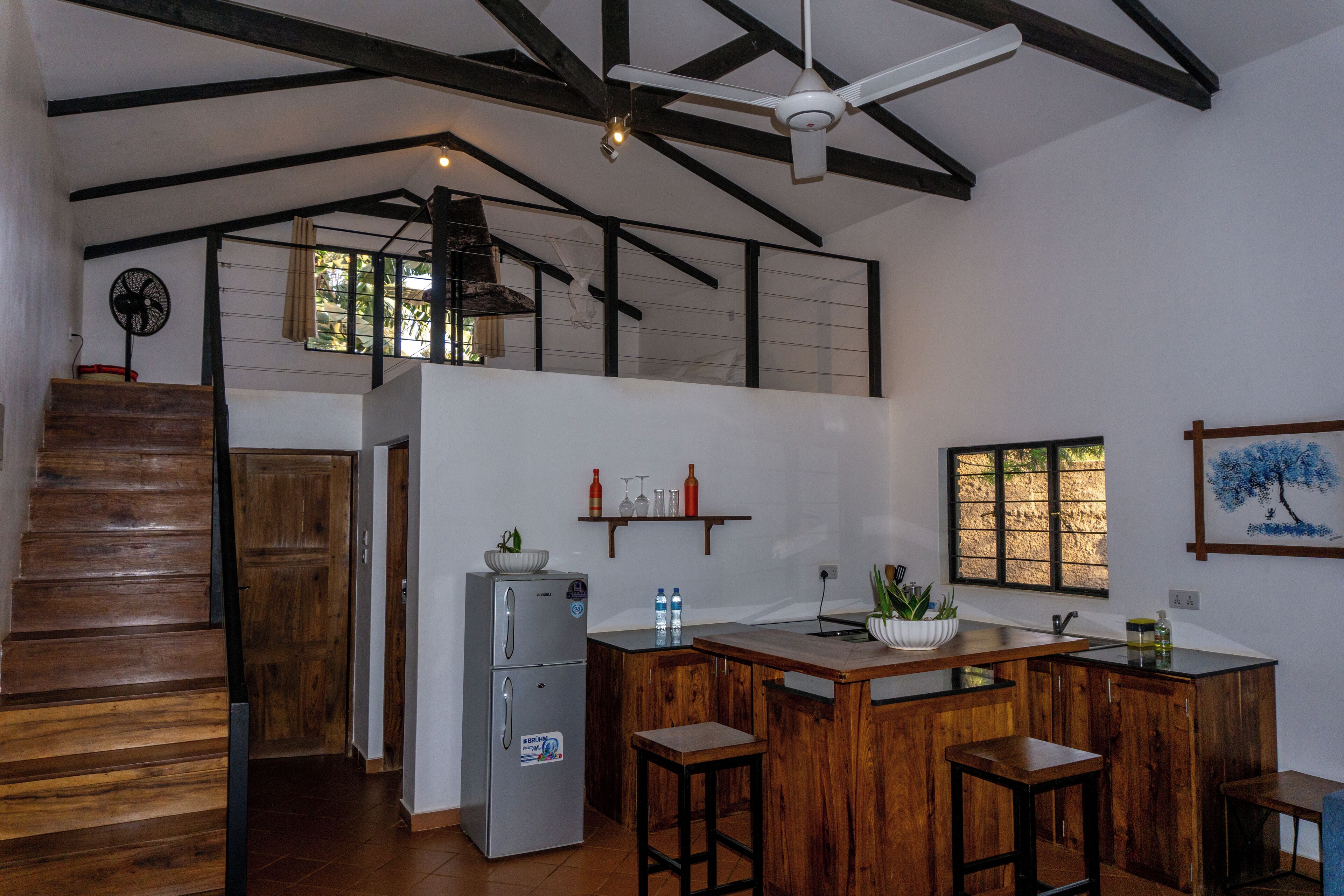 Una cocina con una isla de madera, un refrigerador y un ventilador de techo.
