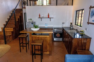 Una cocina moderna con encimeras de madera, una isla central, taburetes de bar, una estufa integrada y una ventana con vistas.