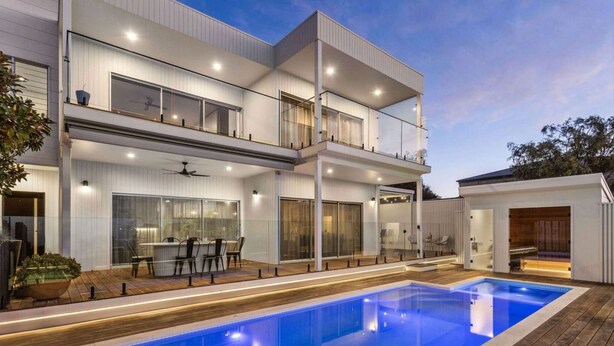 Une maison moderne à deux étages, dotée d’une piscine, de grandes fenêtres et d’un balcon.
