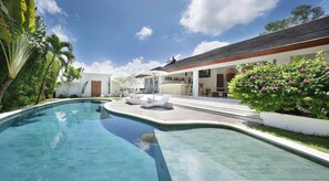 Ein moderner Poolbereich mit Liegestühlen und einer Bar.