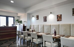 A modern restaurant with booth seating, a reception desk, and wall-mounted artwork.