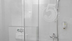 Une salle de bain moderne dotée d’une douche à parois de verre, de toilettes et d’un sèche-mains.