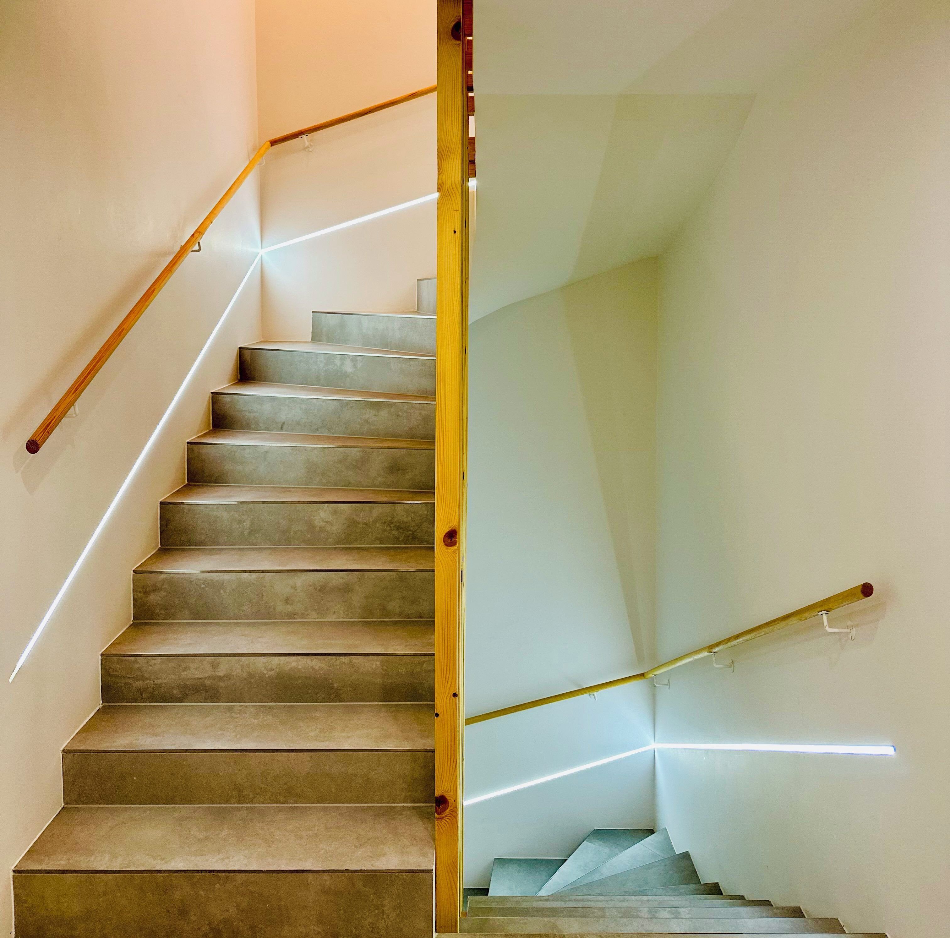 A staircase with a wooden handrail and a glass partition.