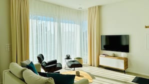 Een moderne woonkamer met een bank, massagestoel, salontafel, televisie en een dressoir.