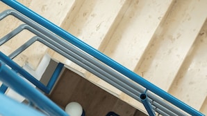Una escalera con peldaños color beige y barandilla azul.
