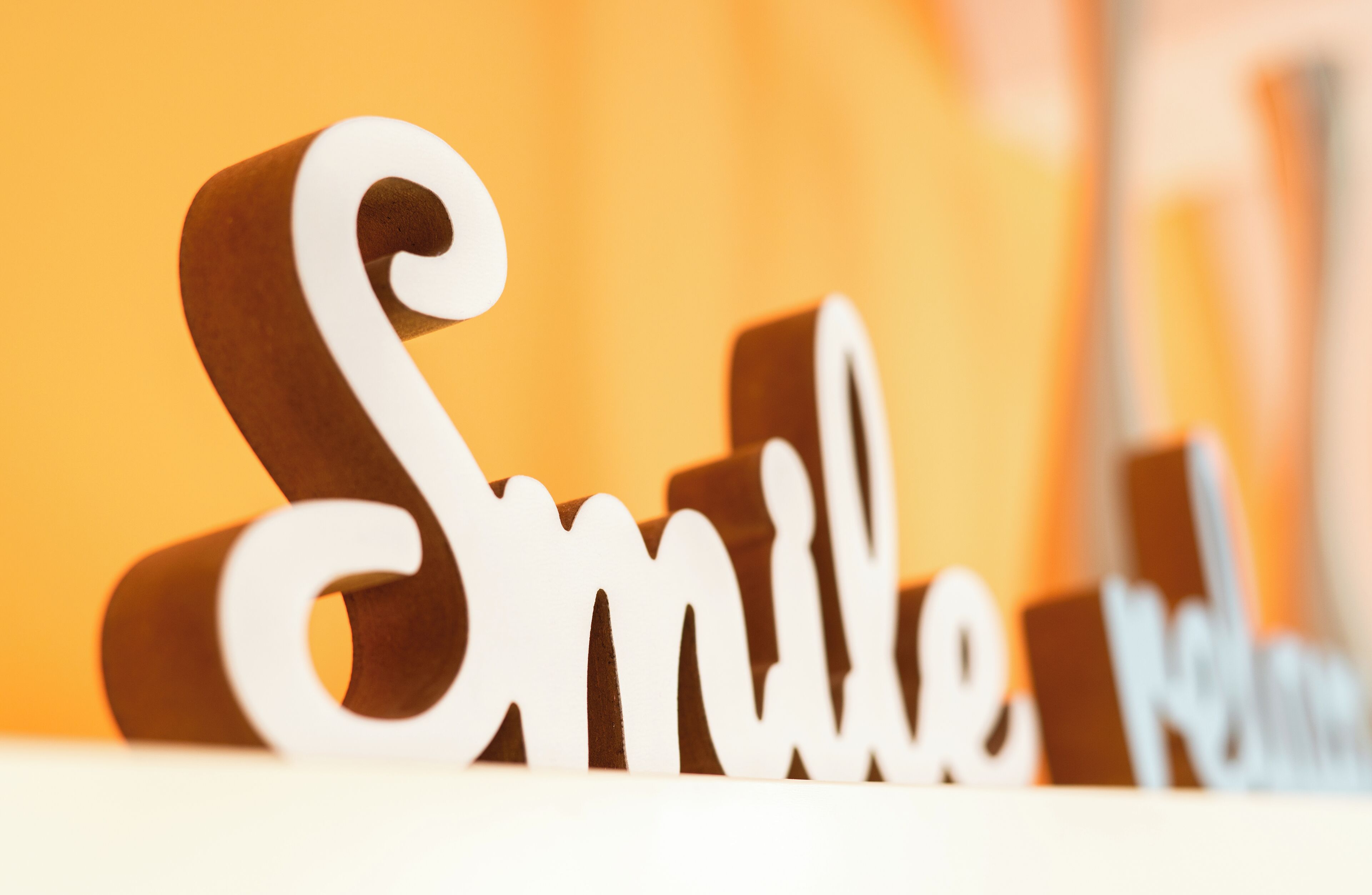 A wooden sign with the word "Smile" in white letters.
