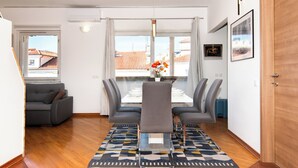 Una sala de estar moderna con comedor, que incluye un sofá, una mesa de comedor con sillas, una mesa de centro y un tapete estampado.