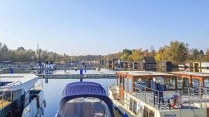 A marina with boats docked, a covered area with a roof, and buildings in the background. - exklusives Appartement in Rechlin (Rechlin)