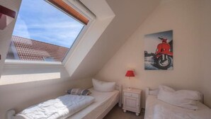 A small, well-lit room with two single beds, a nightstand with a lamp, and a skylight. - Ferienhaus mit großer Terrasse (Rechlin)