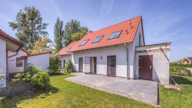 A modern single-story house with a red-tiled roof, a front porch, and a small garden area. - Ferienhaus mit großer Terrasse (Rechlin)