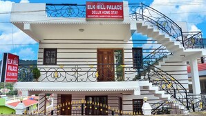 A two-story building with a sign for Elk Hill Palace Deluxe Home Stay. - ELK HILL PALACE (Ootacamund)