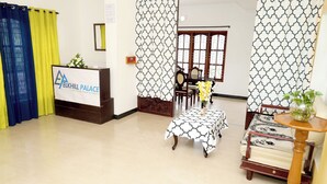 A reception area with a reception desk, a chair, a sofa, and a table with a vase of flowers. - ELK HILL PALACE (Ootacamund)