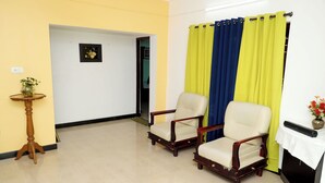 A room with two wooden chairs, a small wooden table with a vase, and a curtain divider. - ELK HILL PALACE (Ootacamund)