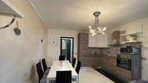Een moderne keuken met witte kasten, een ingebouwde magnetron en een roestvrijstalen oven.