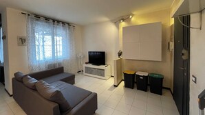 Een woonkamer met een bank, televisie en een wandmeubel.
