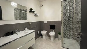 Een moderne badkamer met een grote spiegel, twee wastafels, een toilet en een douchecabine met glazen wanden.