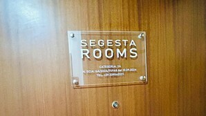 A clear glass plaque on a wooden door with the text "SEGESTA ROOMS" and contact information. - Segesta Rooms  (Rome)