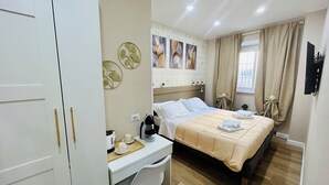 A hotel room with a bed, a desk, and a chair. There are wall decorations and a window with curtains. - Segesta Rooms  (Rome)