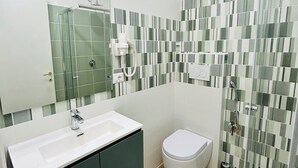A modern bathroom with a white sink, green cabinets, a white toilet, and a shower with a glass door. - Segesta Rooms  (Rome)