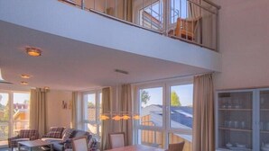 En rummelig opholdsstue med højt til loftet, et spisebord og en sofa.