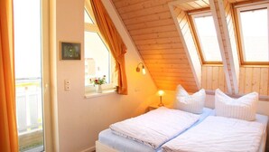 Ett sovrum med två sängar, ett fönster med gardiner, en sänglampa och ett litet bord.