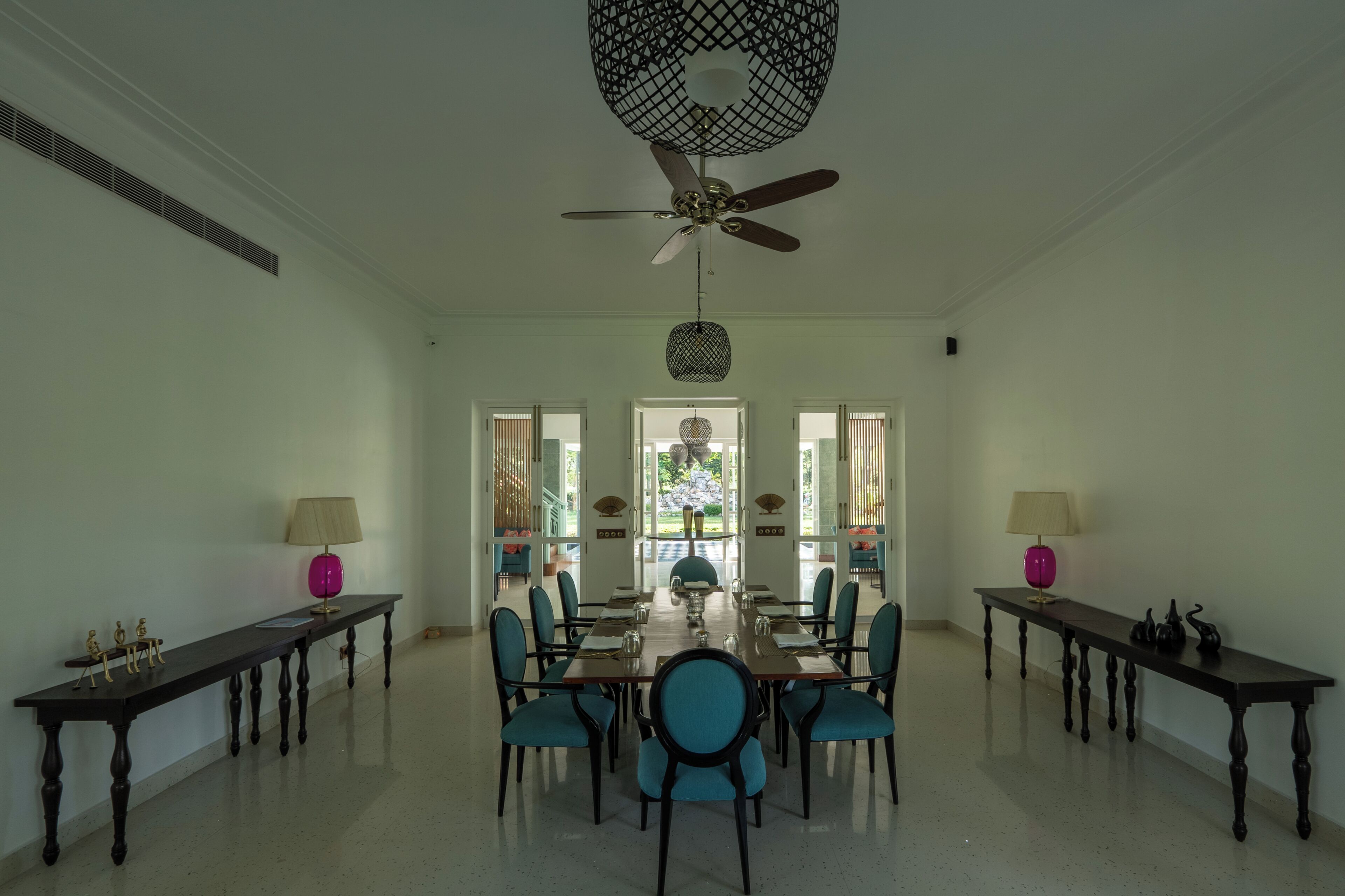 Un espace repas comprenant une longue table, des chaises, des ventilateurs de plafond et des lampes.