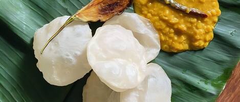 A plate of food with white rice cakes, a yellow curry, and a fried item on a banana leaf.