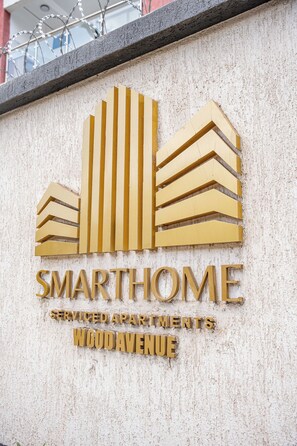 A sign for SmartHome serviced apartments on Woodavenue, featuring a stylized building graphic and text. - Maskan Suites (Nairobi)