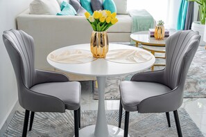 A modern living room with a round white table, two grey chairs, and a gold vase with yellow flowers. - Maskan Suites (Nairobi)