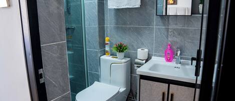 Un baño moderno con inodoro, ducha, lavabo y armarios.