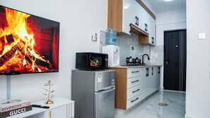 Een moderne keuken met een flatscreen televisie, een koelkast, een magnetron en een waterdispenser.