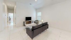 A spacious living room with a modern sofa, a coffee table, and a flat-screen TV on a stand. - 2BD-RemoteWork-Extd Stay Discounts-PetsOK-Central (Corpus Christi)