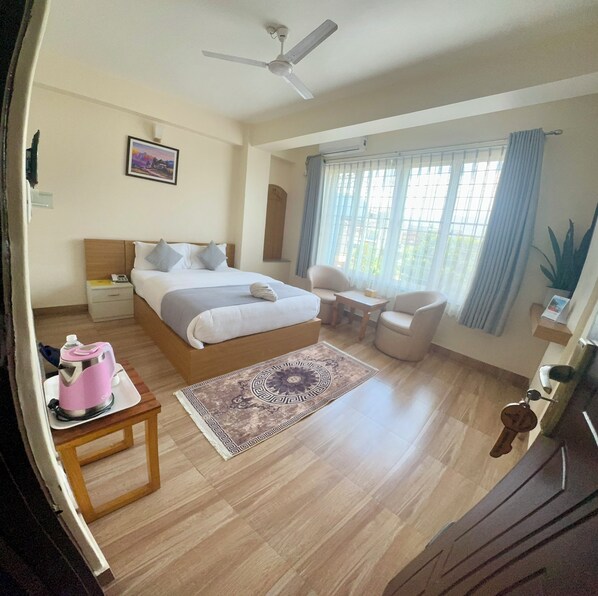 A hotel room with a bed, bedside table, chair, desk, and a ceiling fan.