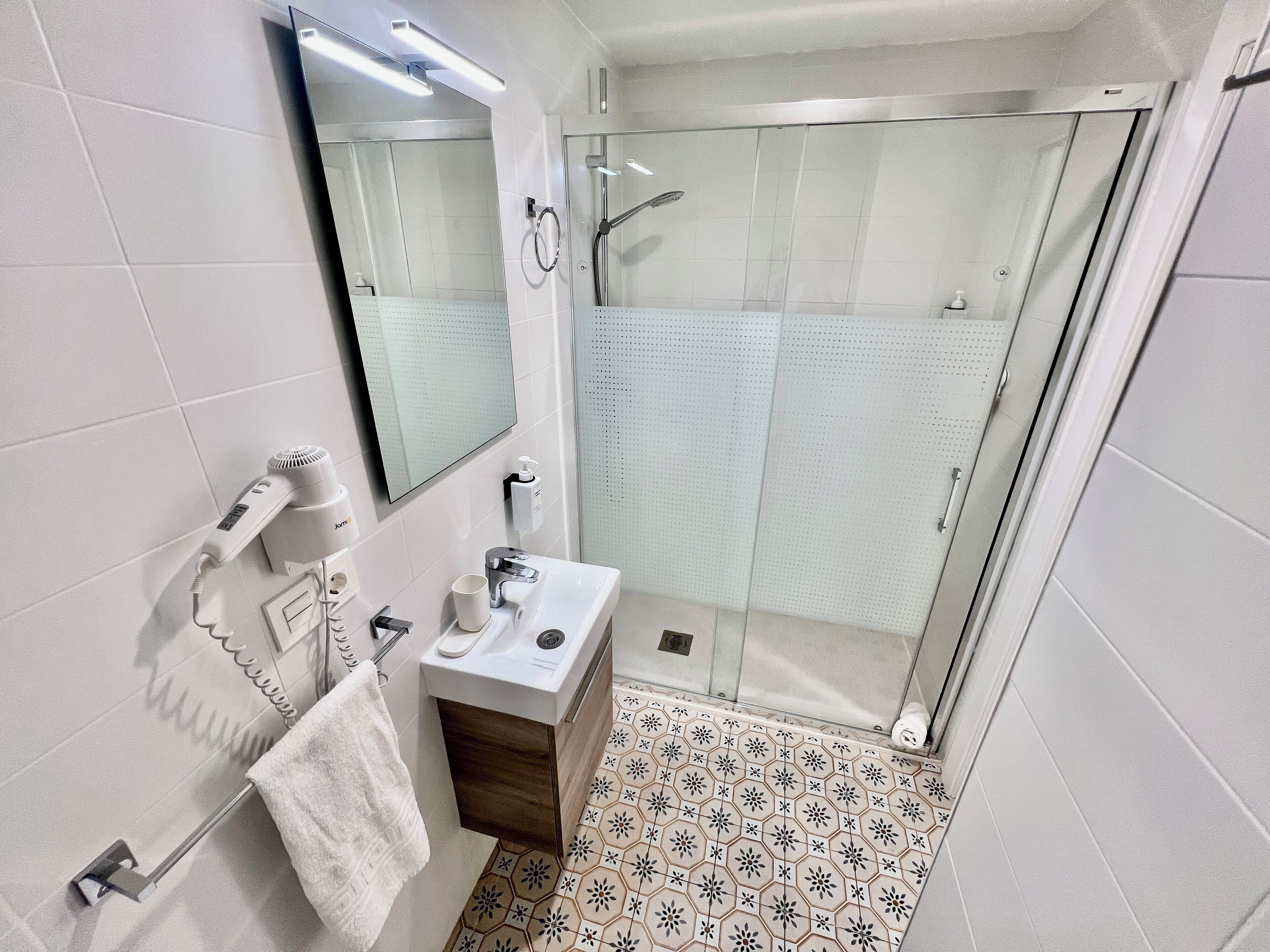 Un bagno moderno con cabina doccia in vetro, lavabo con specchio e portasciugamani.