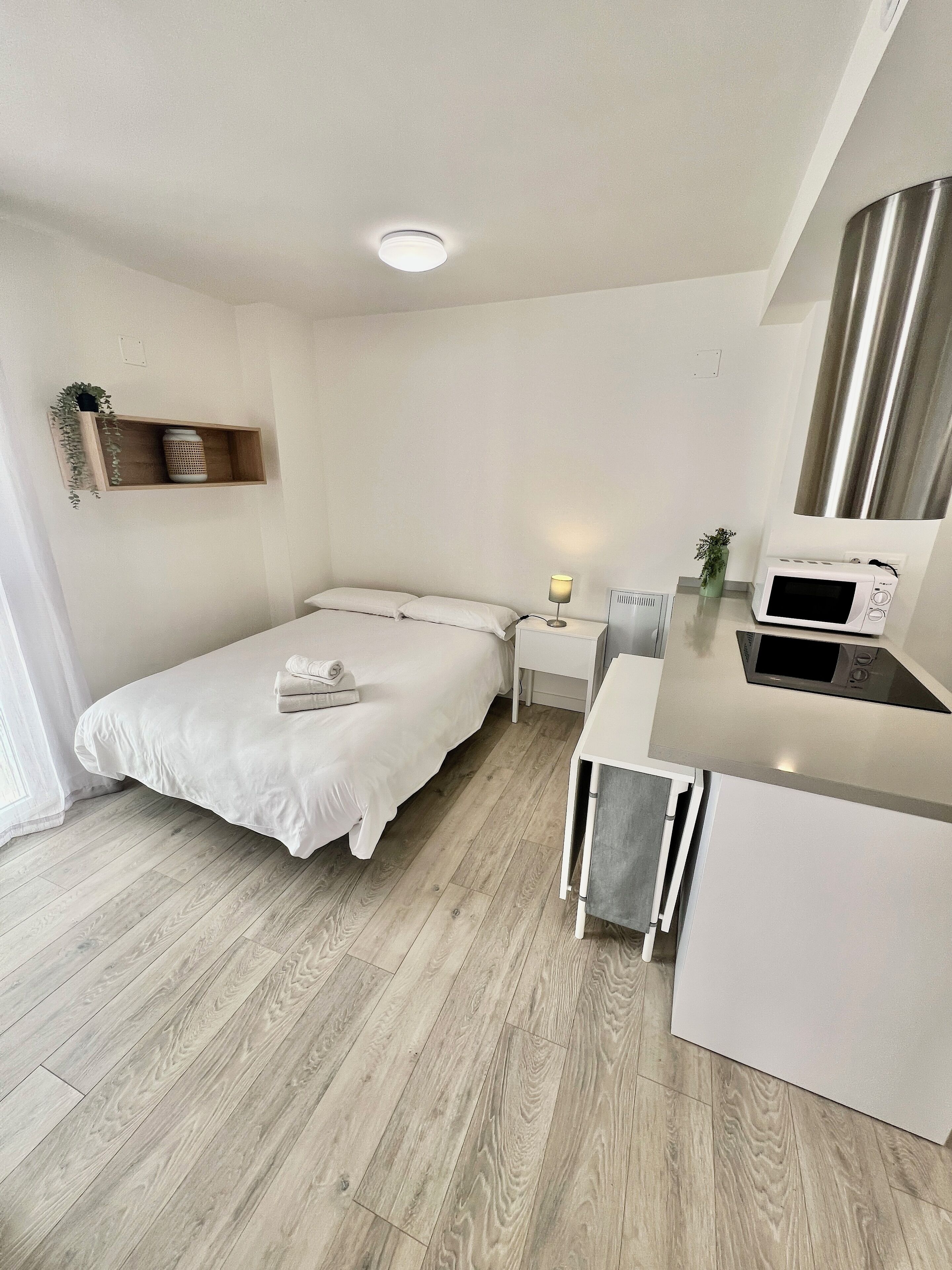 Een moderne, minimalistische slaapkamer met een bed, nachtkastje en een klein bureau.
