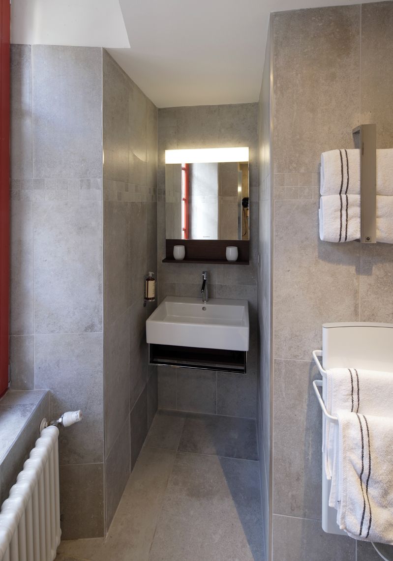 A modern bathroom with a built-in sink, a mirror, and a towel rack.