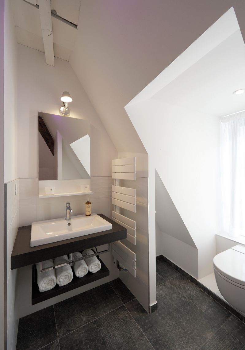 Un baño moderno con lavamanos blanco, espejo y toallero.