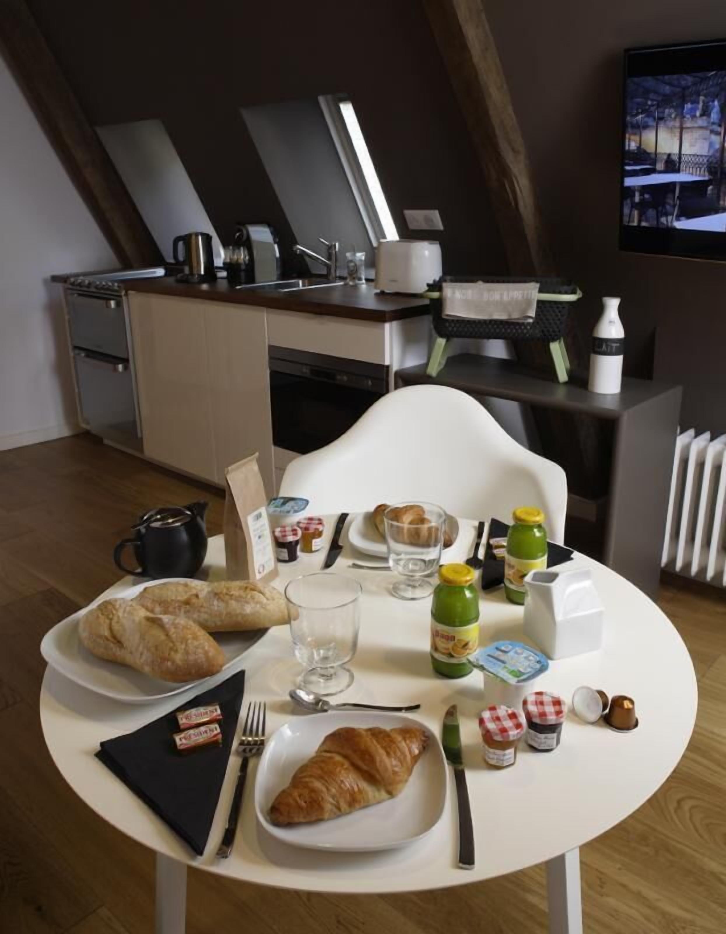 Un comedor con una mesa dispuesta para el desayuno, que incluye croissants, pan y salsas.