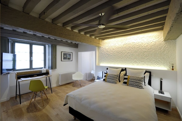 A bedroom with a bed, a desk, a chair, and a window.