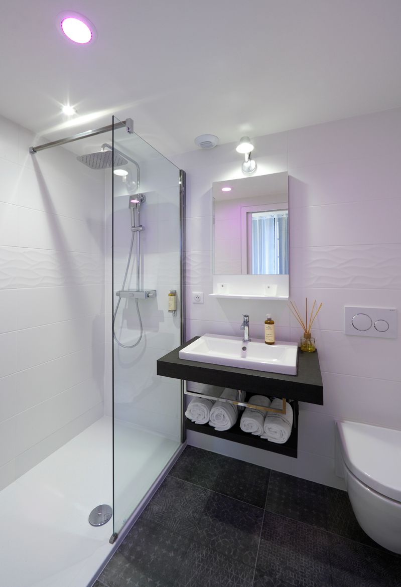 Un bagno moderno con doccia vetro, lavandino bianco e water.