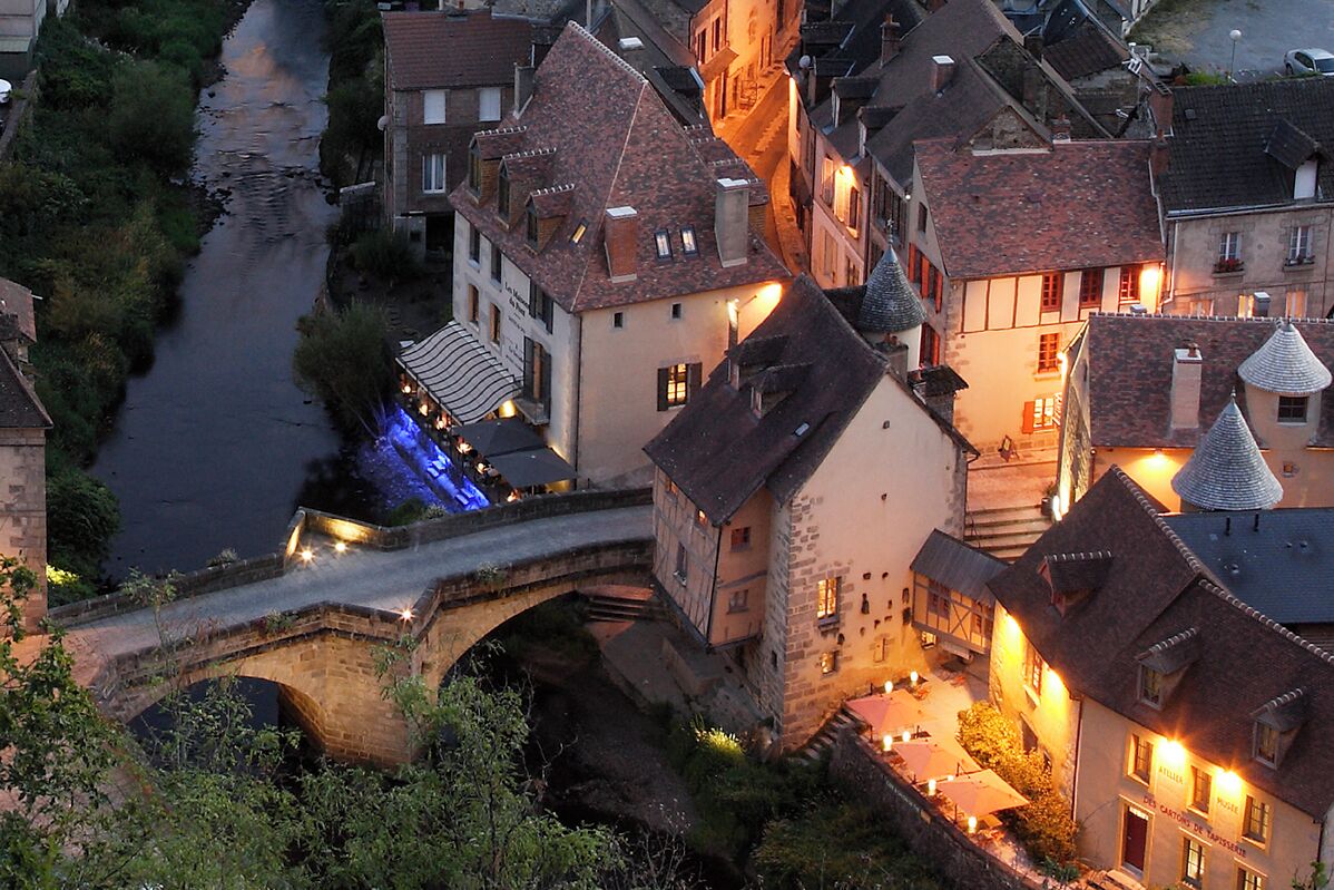 Eine historische Stadt mit einer Steinbrücke, traditionellen Gebäuden und einem Fluss.