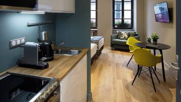 A modern kitchen with a built-in oven, microwave, and coffee maker. There is a dining area with yellow chairs and a small table.
