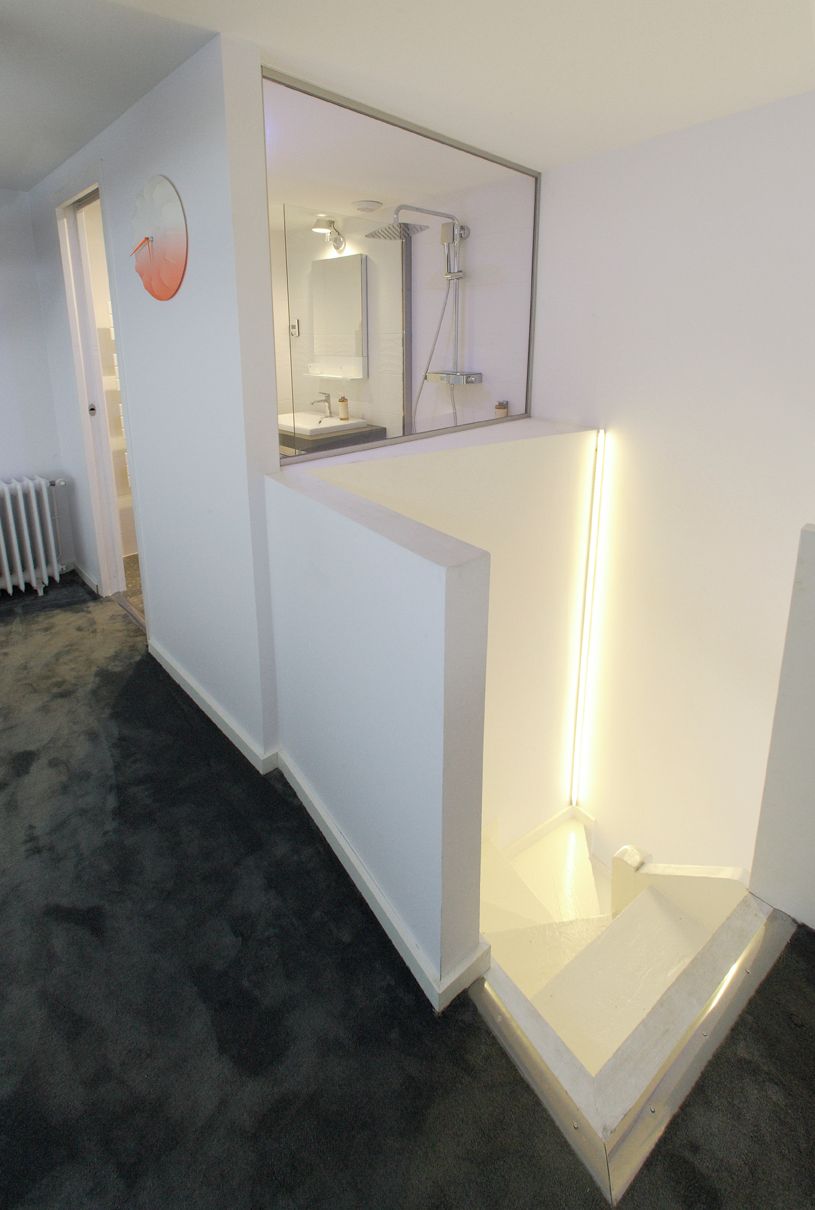 A modern bathroom with a glass shower enclosure, a visible toilet, and a white sink area.