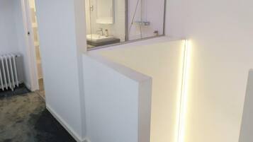 A modern bathroom with a glass shower enclosure, a visible toilet, and a white sink area.