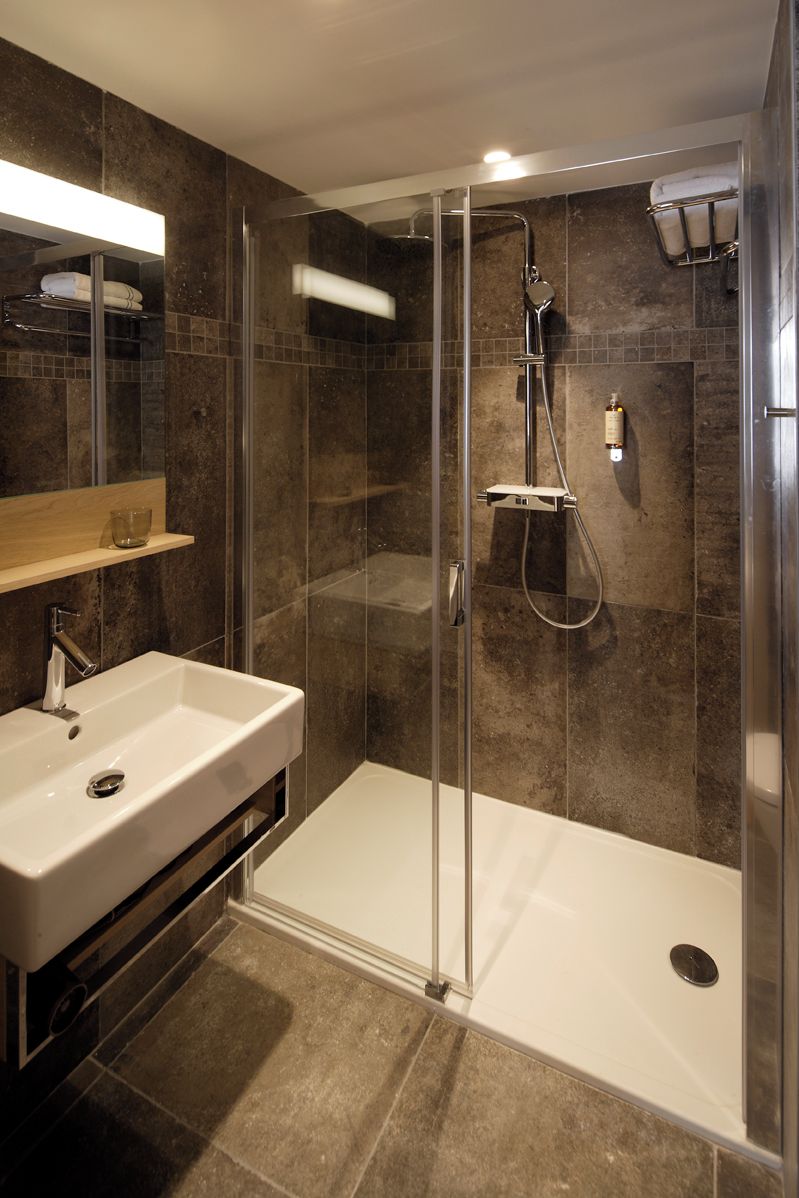 Une salle de bain moderne avec une douche à parois de verre, un lavabo blanc et un miroir au-dessus du lavabo.