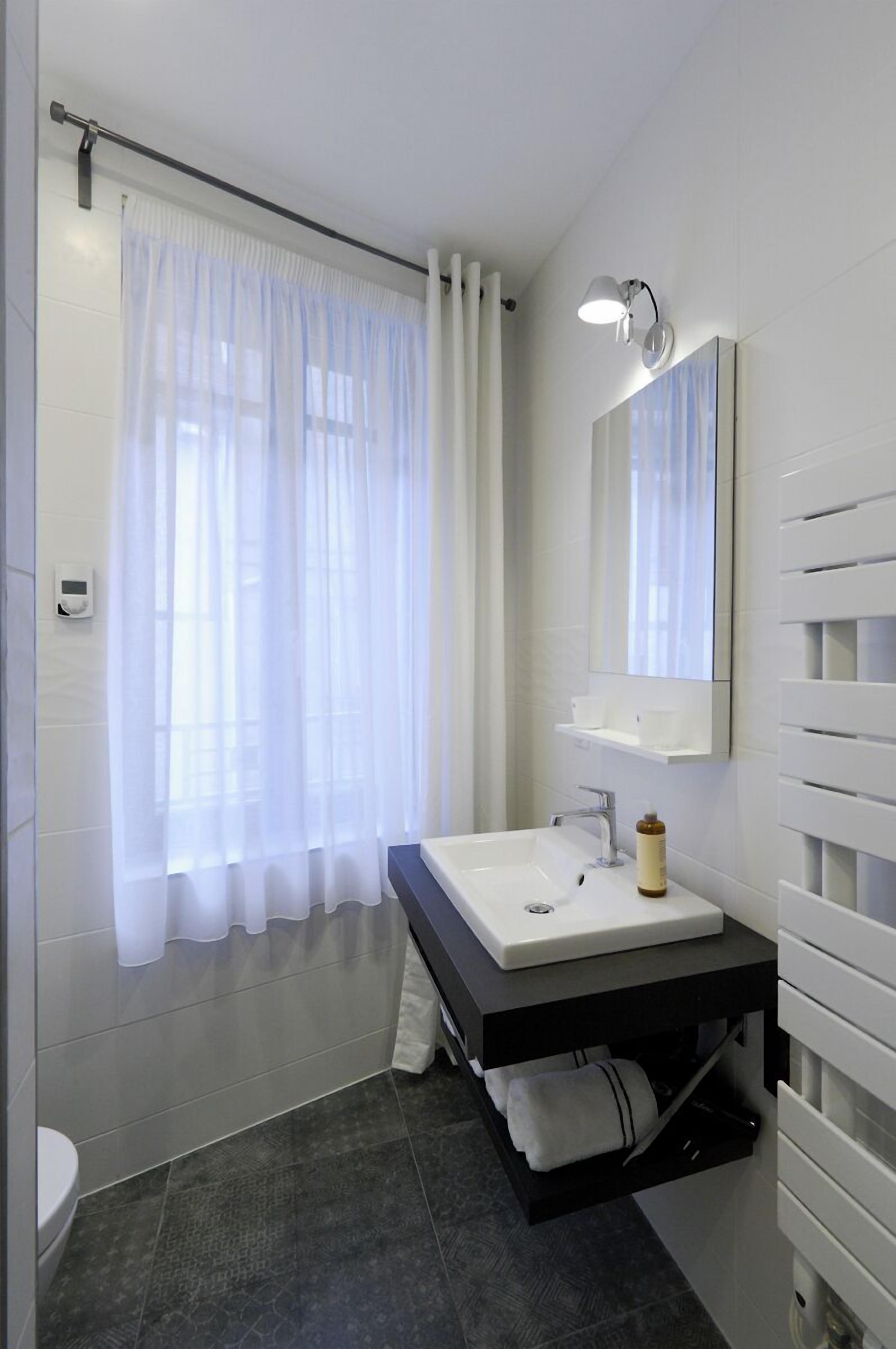 A modern bathroom with a white sink, a mirror, and a shower curtain.